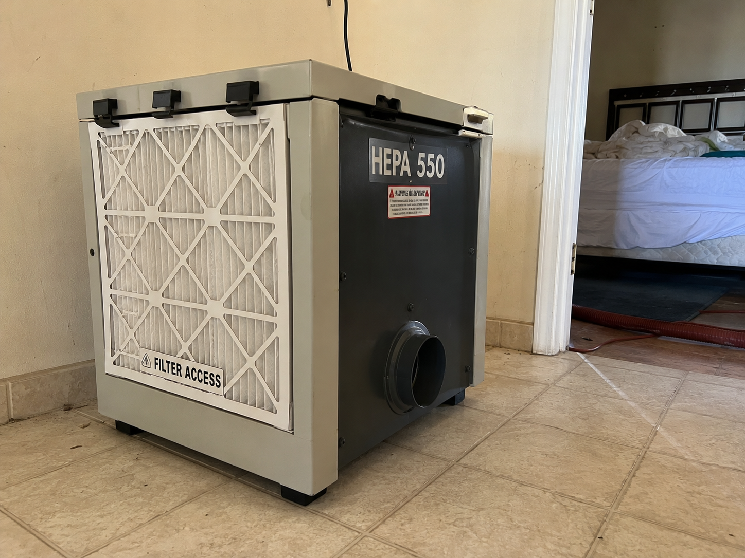 HEPA 550 negative-air scrubber running in a contained Pensacola bedroom during mold remediation